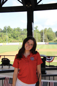 A woman smiles in the stands of a baseball stadium